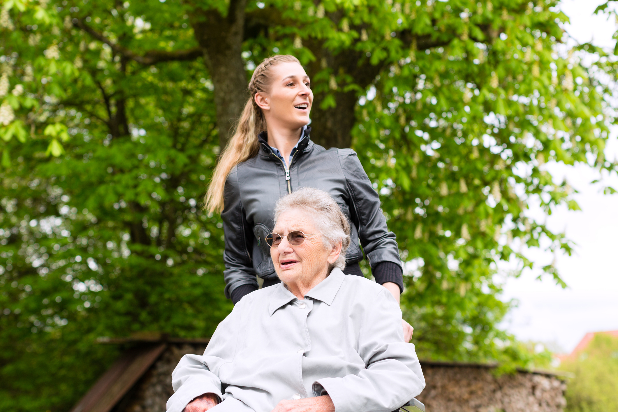 Young woman pushing an older person in a wheelchair