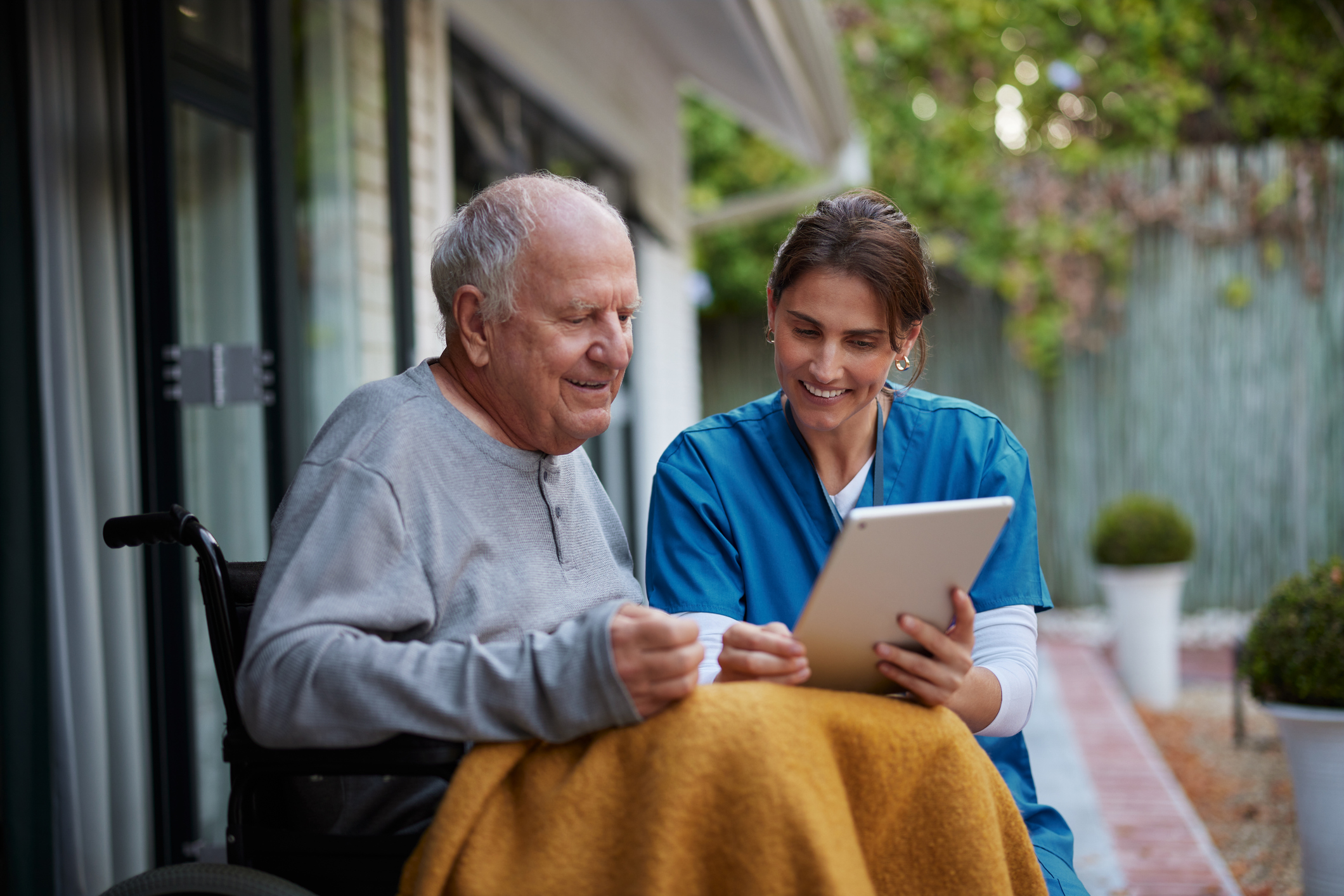 an older person looking at an iPad with a healthcare provider
